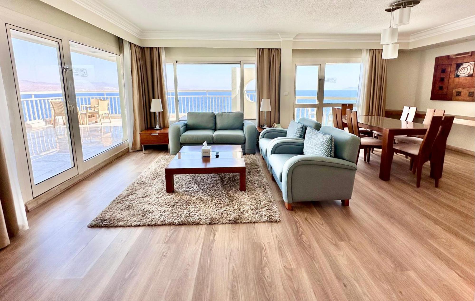 Steigenberger Hotel & Nelson Village, Taba Exterior foto The photo shows a modern and spacious living area with a beautiful view. It features light-colored wooden flooring and large windows that allow plenty of natural light. In the center, there's a plush area rug with a glass coffee table on it. Surround